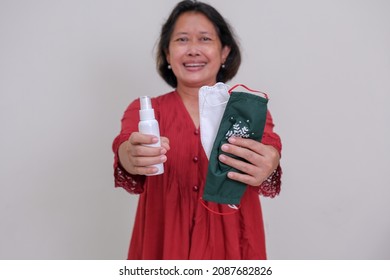 Woman In Red Dress Offering Two Masks And A Bottle Of Hand Sanitizer