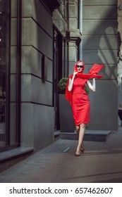 Woman In A Red Dress Is Walking Around The City.