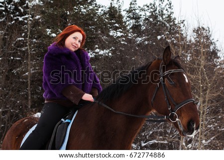 Woman with red hair and big horse outdoor in winter day