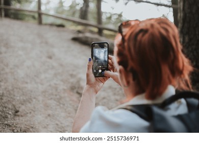 a woman with red hair films nature views on her phone while deep in the forest in Estonia - Powered by Shutterstock