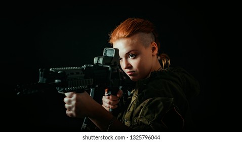 Woman with red hair, hold machinegun and takes aim at the sight in military uniform. horizontal background