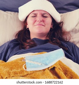 Woman With Red Hair Lies In Bed Sick With Coronavirus With A Cold Compress On Her Head