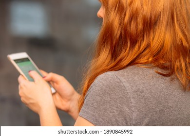 Woman with red hair scrolling on her phone, over the shoulder look, social media concept - Powered by Shutterstock