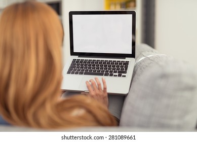 Woman With Red Hair Sitting On Sofa With Laptop Computer, Perspective From Behind Over Shoulder Looking At Blank Computer Screen