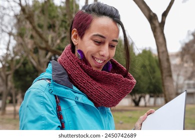 A woman with red hair is smiling and holding a book. - Powered by Shutterstock