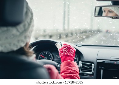 Woman in the red jacket, hat and christmas gloves is driving on the highway at the winter snowfall.  View from the back seat of the car. concept. 