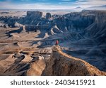 Woman in red jacket on cliff above colorful canyon. Moonscape overlook. Hanksville. Utah. USA