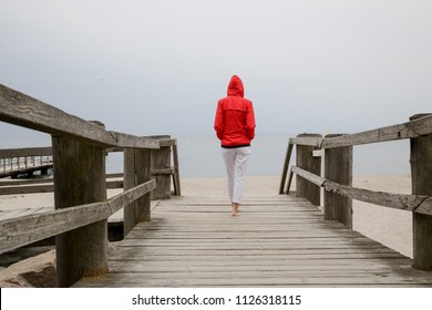 
Woman in red jacket standing on the wooden pier, back view