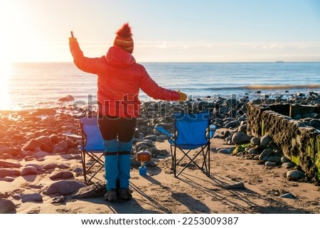 Woman in red  jacket walking alone on the seaside on cold winter day. Travel Lifestyle concept