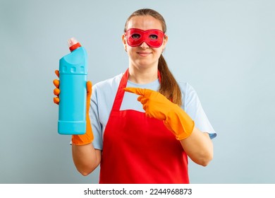 Woman in red mask, rubber gloves and apron holding cleaning agent bottle