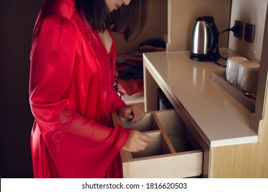 A Woman In A Red Nightgown Opens A Drawer To Find Something In The Kitchen. Can't Find, Lost Items