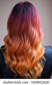 Woman and red   orange gradient dyed long curly hair  back view