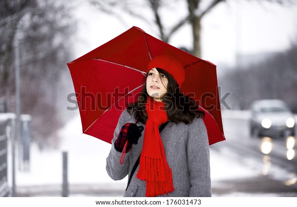 A woman\
with a red scarf holding a red\
umbrella.