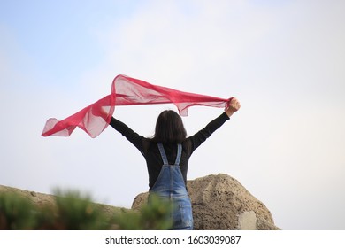 Woman With Red Scarf Standing At Windy Mountaintop