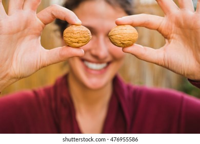 Woman with red shirt holding some walnuts between the fingers