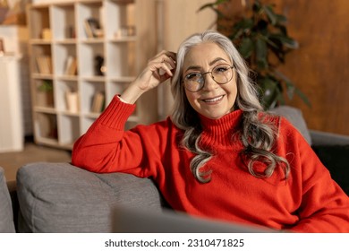 Woman in red shirt watching something on laptop - Shutterstock ID 2310471825