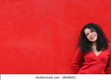 Woman In Red Smiling Wearing Red Sweater Against Red Wall Background