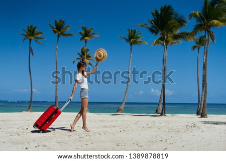A woman with a red suitcase is resting on an island near the ocean                    