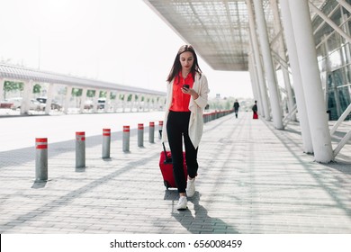 Woman With Red Suitcase Walks Along The Airport And Talks On The Phone