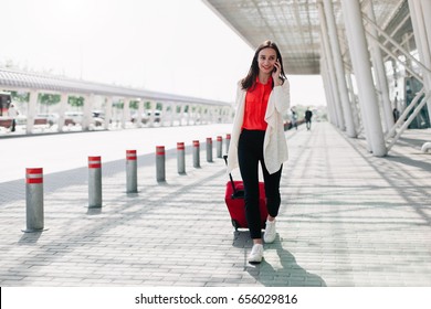 Woman With Red Suitcase Walks Along The Airport And Talks On The Phone