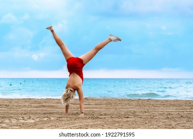 Woman In Red Swimsuit Doing Cartwheel On The Beach