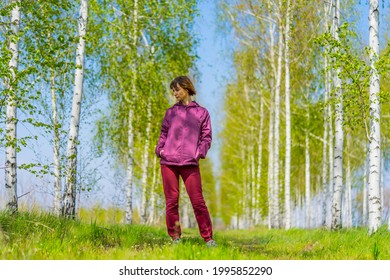 A Woman In A Red Tracksuit Stands In A Birch Grove