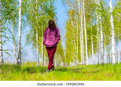 A Woman In A Red Tracksuit Stands With Her Head Bowed In A Birch Grove.