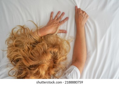 Woman With Redhead Hair And Hands On Bedsheet The Bed. Concept Of Good Morning, Sleep, Time For Yourself.  Woman With Redhead Hair Grasping Hand The Bed Sheet In Moment Of Sexual Pleasure On The Bed