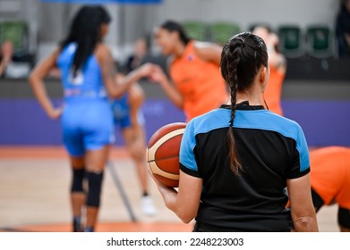 Woman referee keeps the ball before basketball match. In the background greeting the players. - Powered by Shutterstock