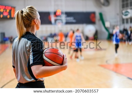 Woman referee keeps the ball during basketball match.