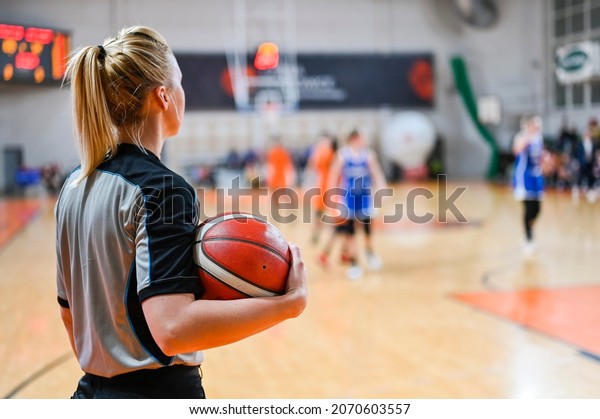 Woman\
referee keeps the ball during basketball\
match.