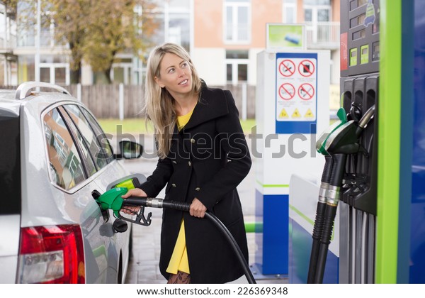 Woman refilling car with\
fuel