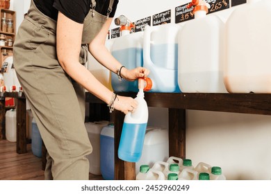 A woman refills a blue detergent bottle from a large dispenser in an eco-friendly, zero waste shop. Text: "Dishwasher, detergent" - Powered by Shutterstock