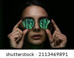 Woman with reflection of matrix code in her tinted glasses on dark background