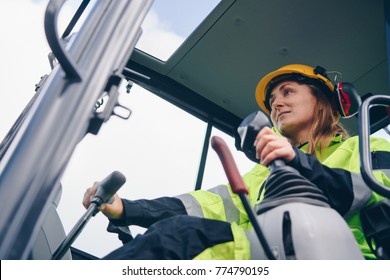 Woman in reflective clothing operating heavy equipment