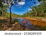 A woman refreshes herself in a shallow river along the Cascades Walk in the tropical monsoonal rainforest of Litchfield National Park, 120 km from Darwin, Northern Territory, Australia
