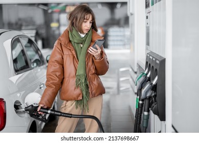 Woman refueling car with gasoline, using smartphone to pay. Concept of mobile technology for fast refueling without visiting the store - Powered by Shutterstock