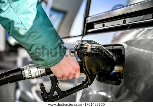 Woman refueling\
at a gas station. Pumping\
gas.