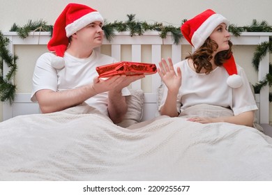 Woman Refuses A Gift On A Bed Decorated For Christmas On New Year Eve, Family Couple In Home Bedroom