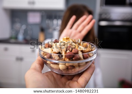 Woman Refusing Bowl Of Nut Food Offered By A Person At Home