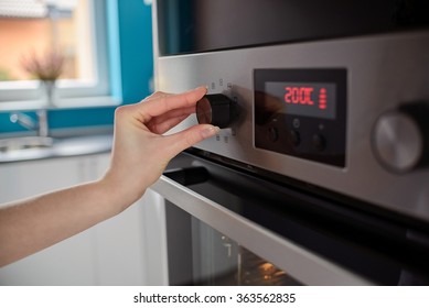 Woman regulates the temperature of the oven - 200C