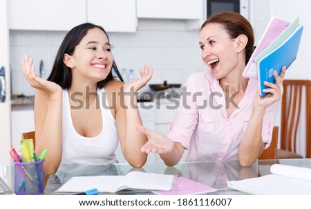 Woman rejoicing at good marks of her teenage daughter in kitchen