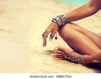 Woman In Relaxation On Tropical Beach with sand , body parts  . Tanned girl in Lotus position with silver jewelry,bracelets and rings with turquoise.Boho style