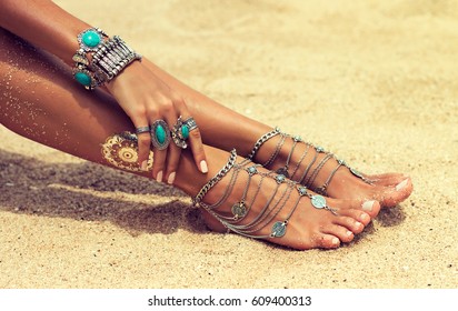 Woman In Relaxation On Tropical Beach with sand , body parts  . Tanned girl in Lotus position with silver jewelry,bracelets and rings with turquoise.Boho style
