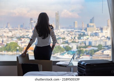 Woman relaxing at apartment or hotel after business meeting. Business trip. Booking hotel during your vacation. Businesswoman in luxury room, looking spectacular metropolitan city through hotel window