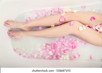 Woman relaxing in bath with foam and petals, closeup of female legs - Powered by Shutterstock