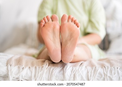 Woman relaxing in bedroom, female feet with dry cracked skin close-up, foot care concept, home interior - Shutterstock ID 2070547487