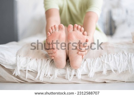Woman relaxing in bedroom, female feet with dry cracked skin close-up, foot care concept, home interior