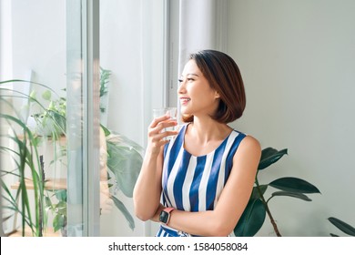 Woman relaxing behind the door/window and holding a cup of tea