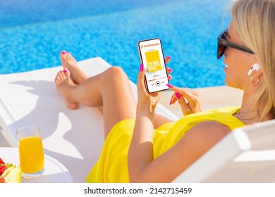 Woman Relaxing By The Pool On Vacation And Listening To Audiobook By Using Phone And Wireless Earbuds